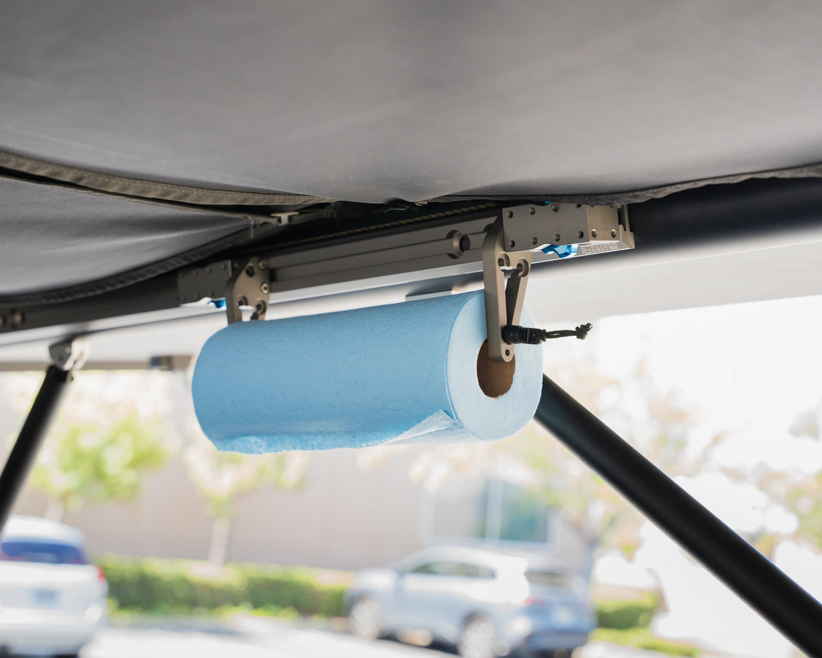 MODmount paper towel holder mounted under a camper roof rail holding a blue roll
