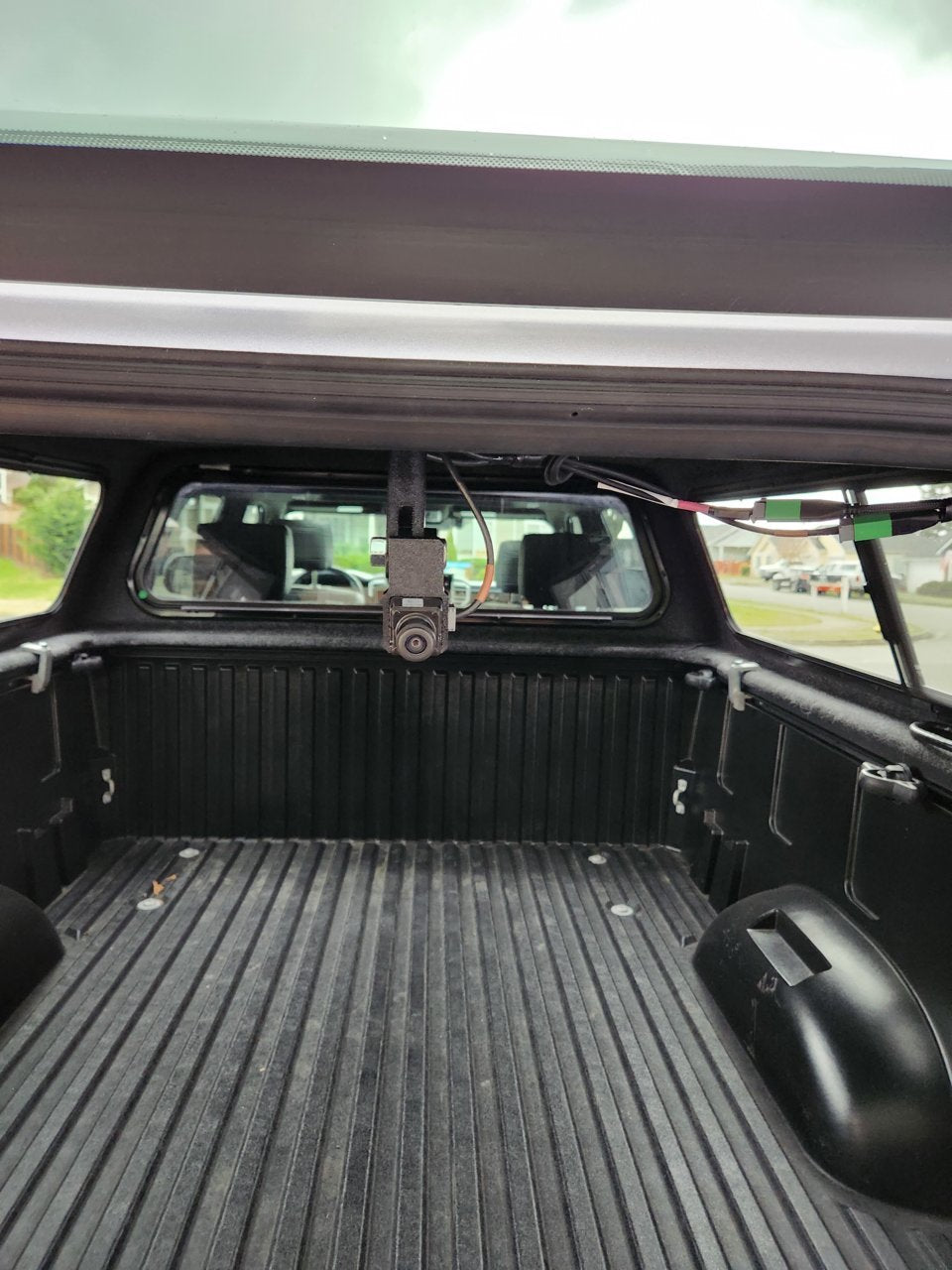 Pivot arm camera mount hanging inside a topper over a Tacoma bed