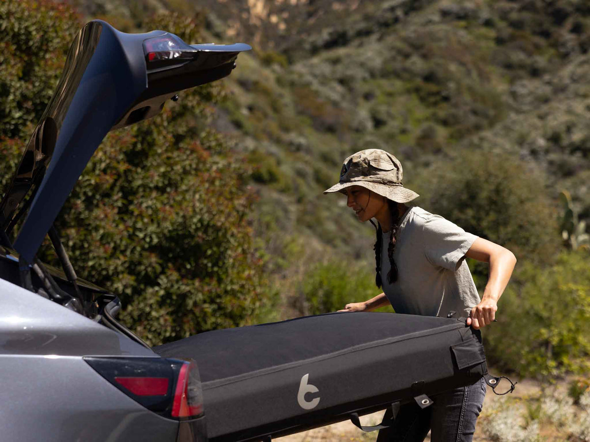 C6 Rev Tent (HellaStorm) – person lifting the packed bag at the back of a vehicle