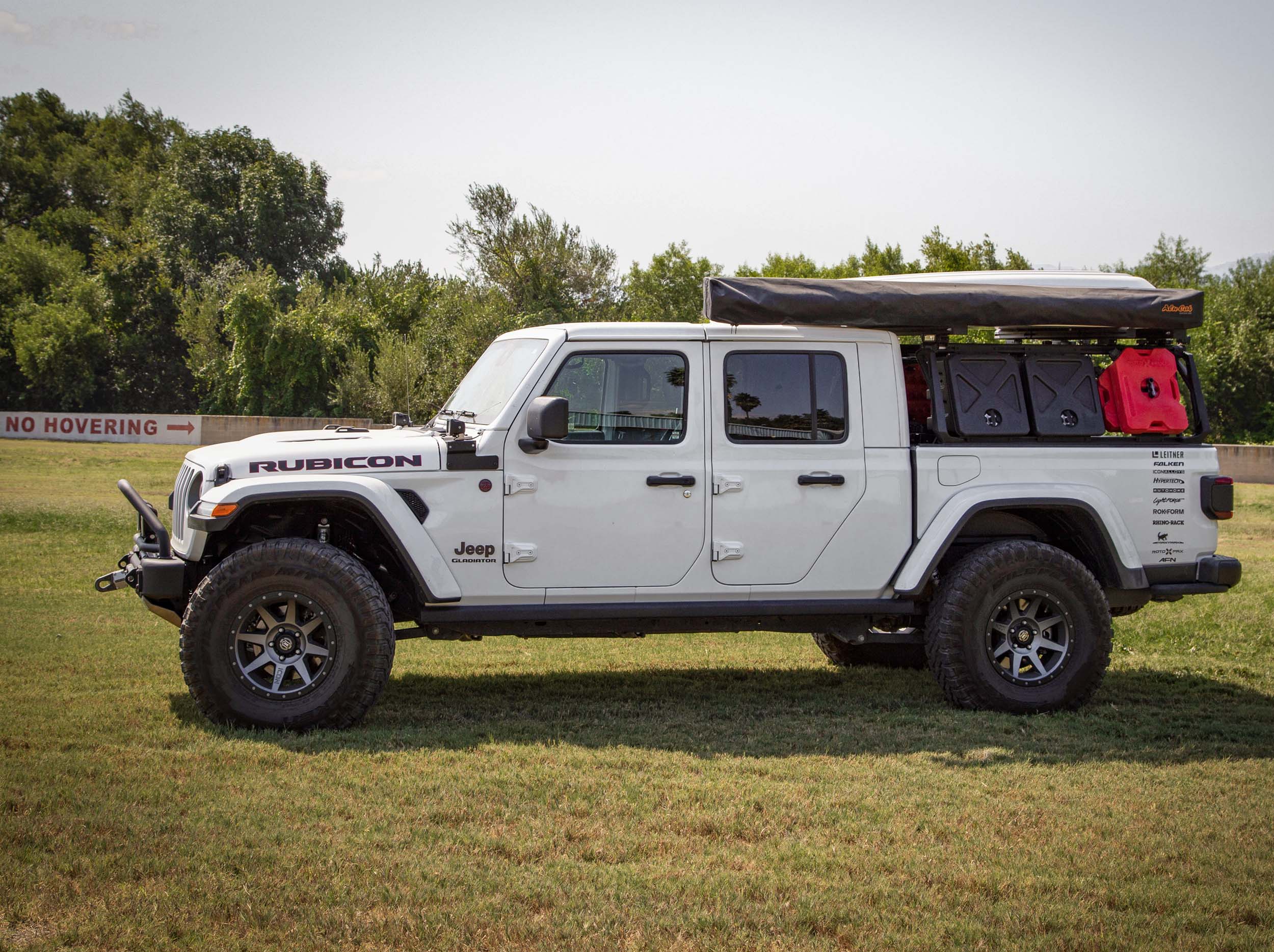 SIDE VIEW OF WHITE JEEP OUTSIDE WITH HD AWNING BRACKET MOUNTED TO THE ACS ROOF RACK