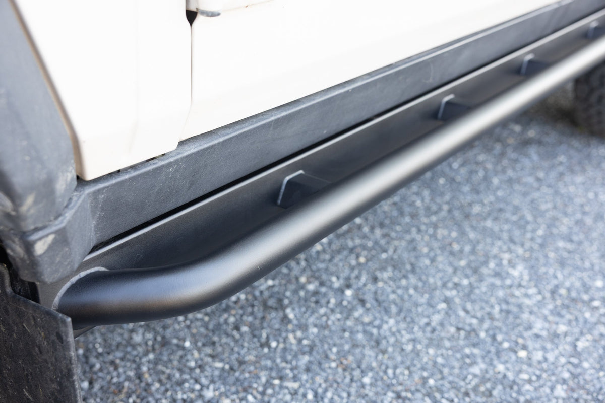 Black rock slider installed along the lower door sill of a white vehicle