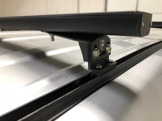 K9 load bar and mounting foot on a silver SUV roof, close-up