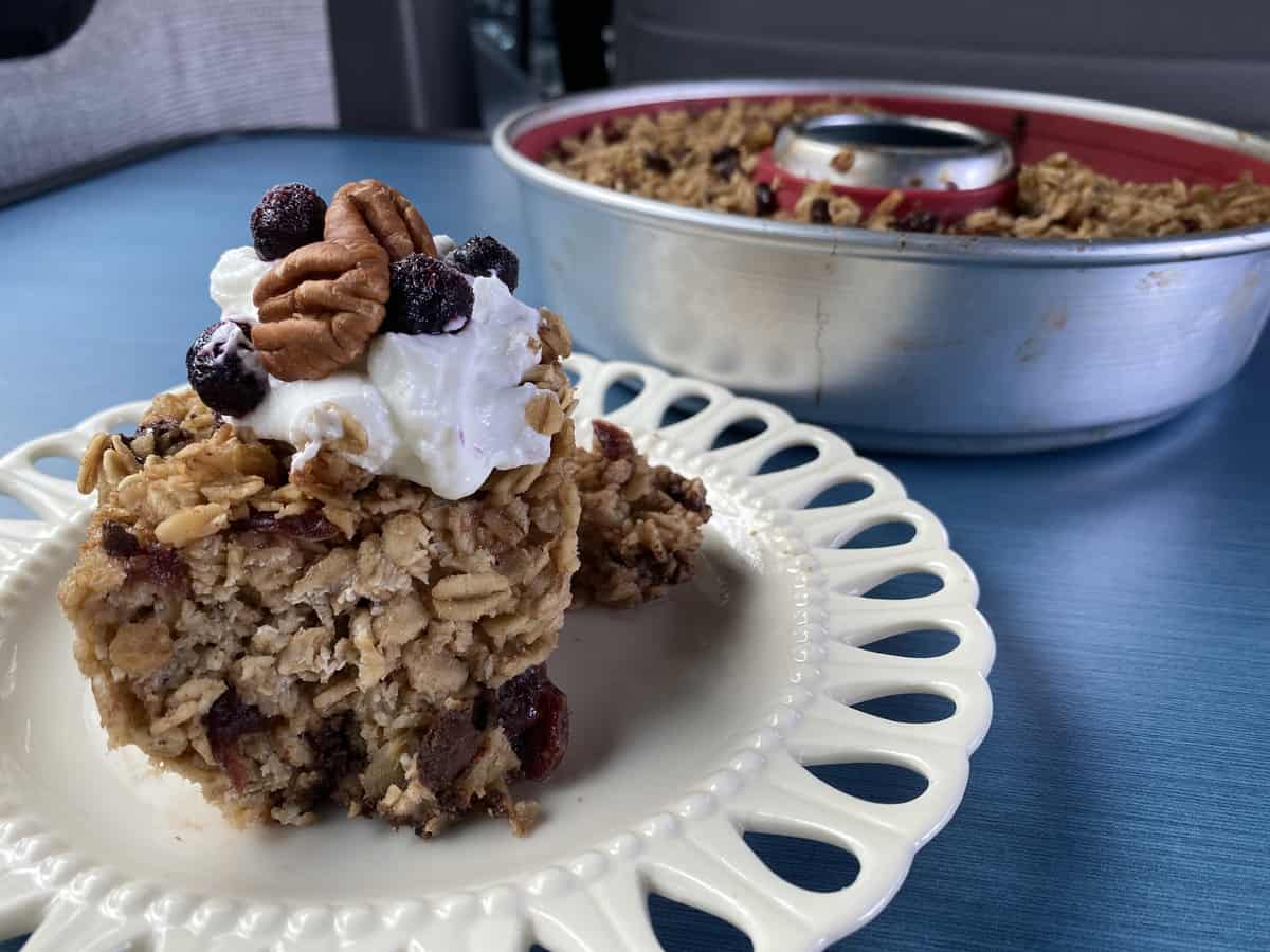 Close-up of a baked fruit and oat dessert on a plate next to the Omnia oven's baking pan, indoor kitchen setting