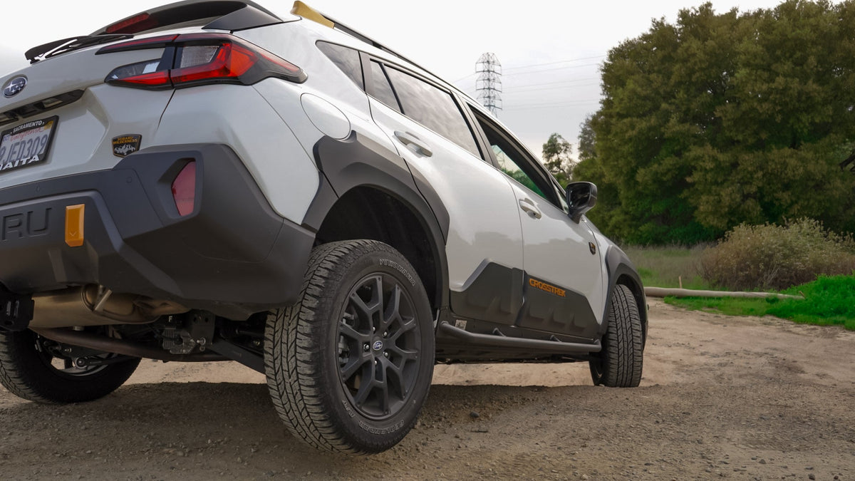Rear three-quarter view of a Subaru SUV with rock sliders along the lower body