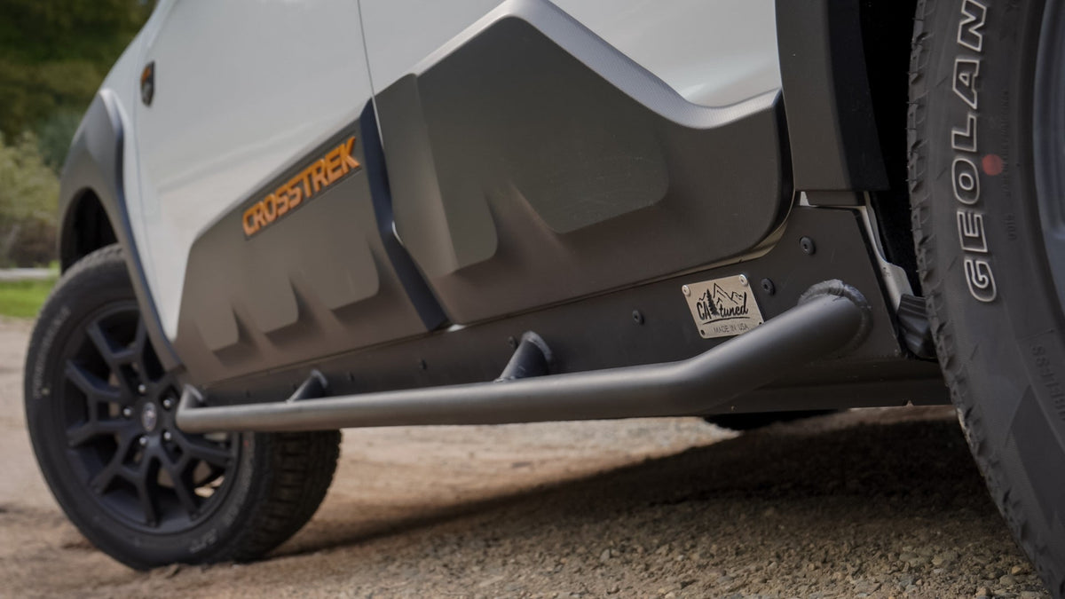 Side view of a white SUV with a black rock slider tube below a door decal