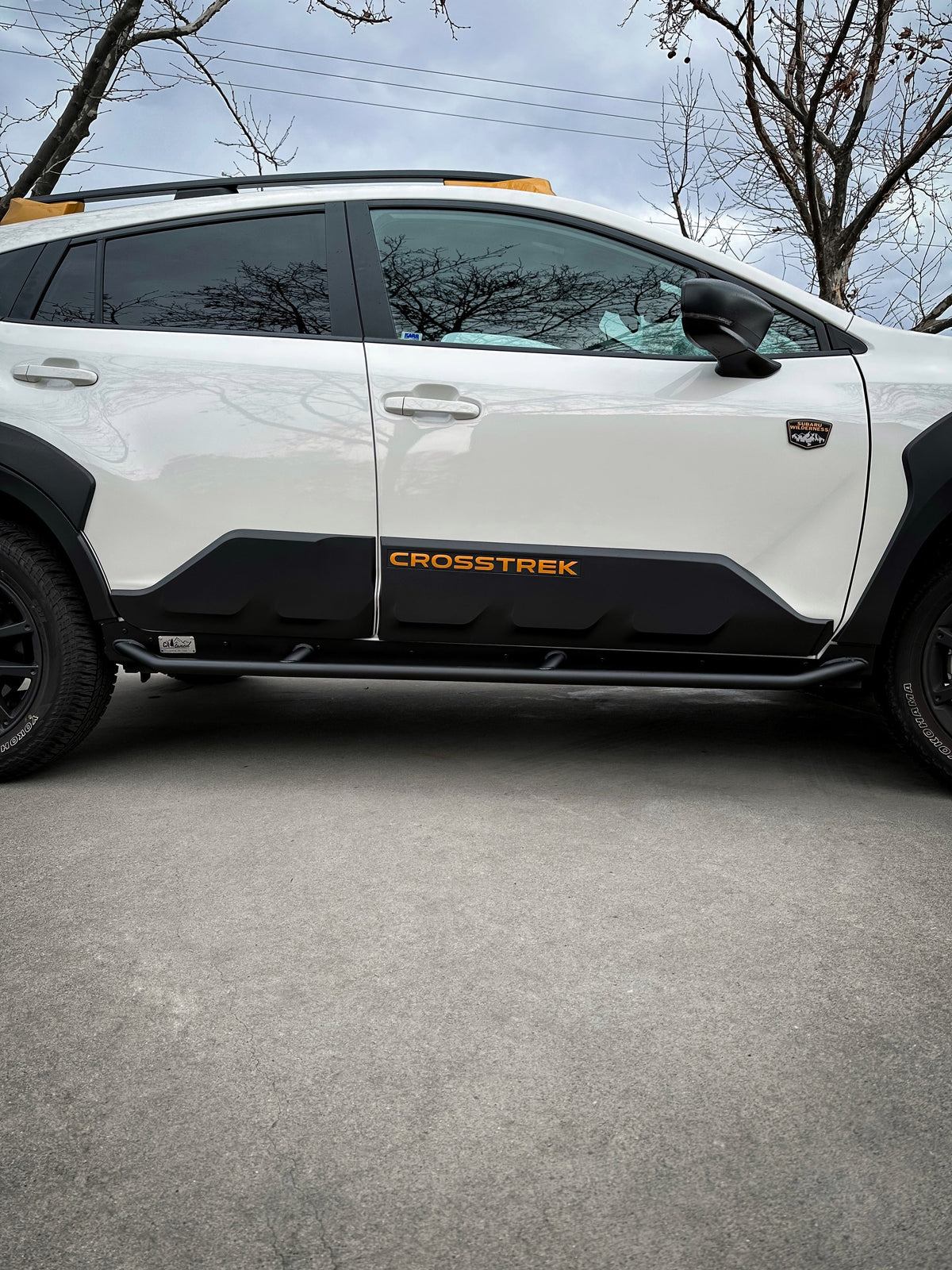 Side of a white SUV with a black rock slider along the lower body