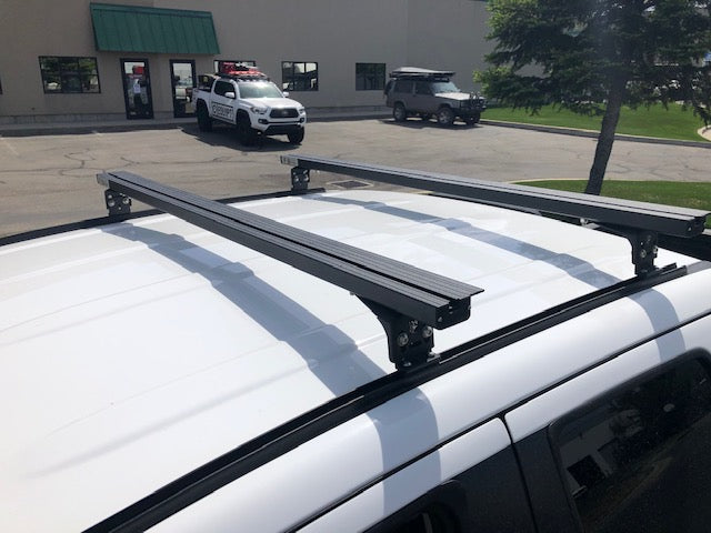 Eezi-Awn K9 load bars on a white vehicle roof, angled view
