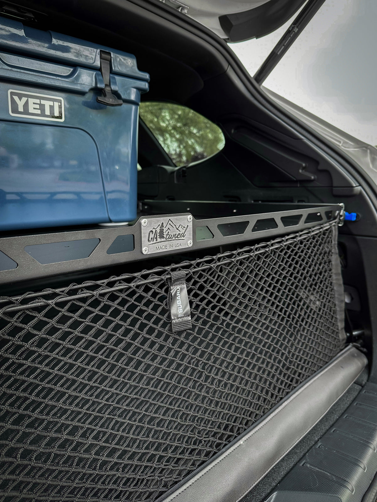 Blue cooler on the cargo shelf with a cargo net hanging below it