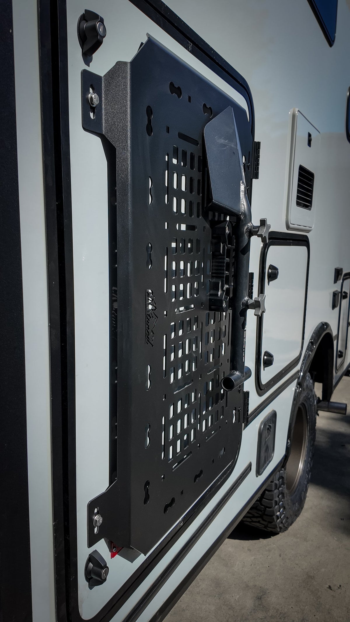 Black MOLLE panel with a bracket on a van door