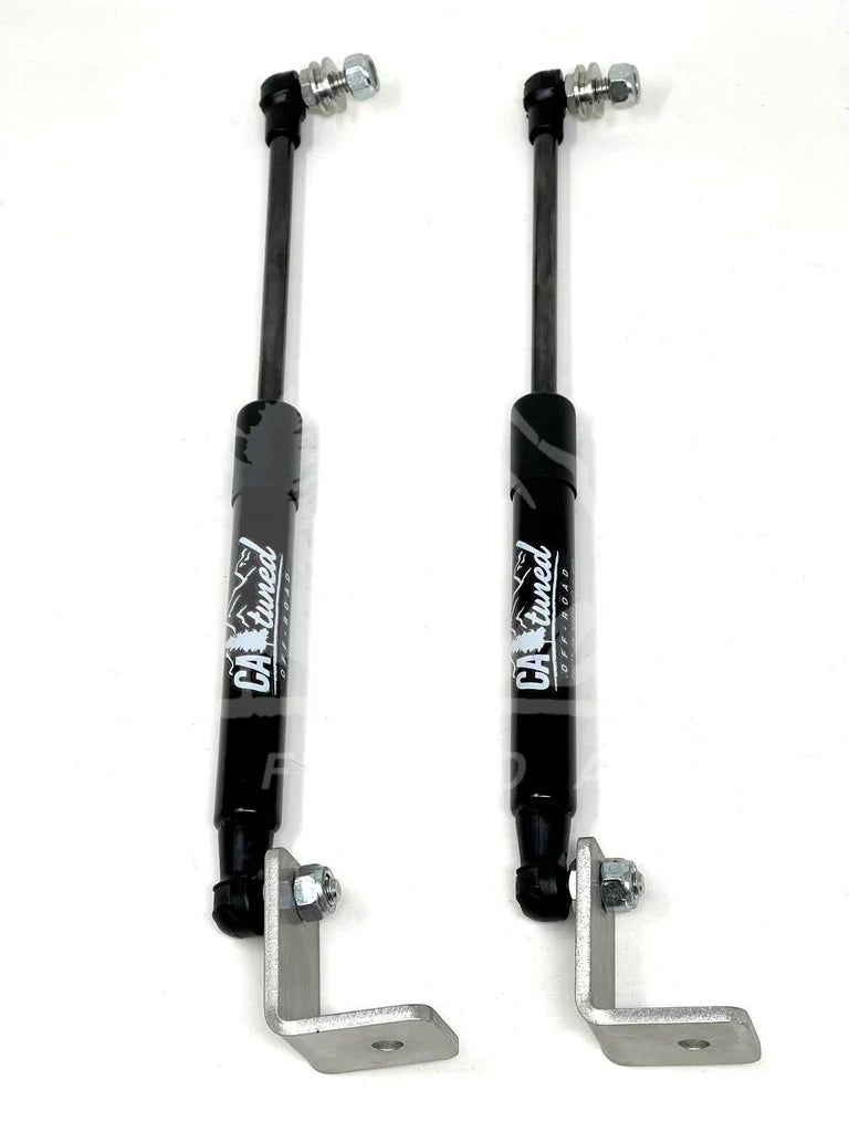Pair of black gas hood struts with lower mounting brackets on a white background