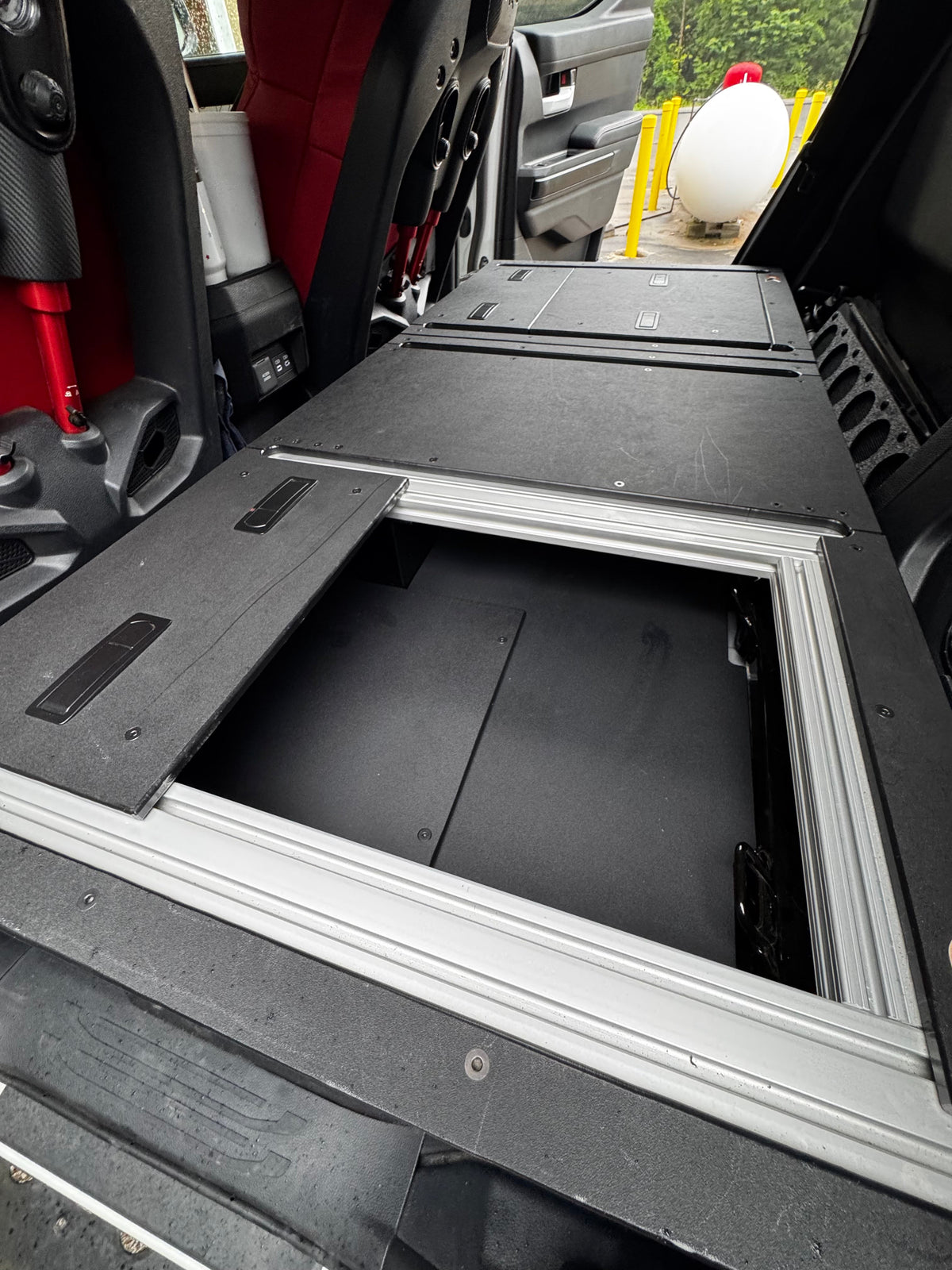 CargoKits Rear Seat Delete in a Tacoma TRD Pro Hybrid, view of the platform beside the red TRD Pro seat