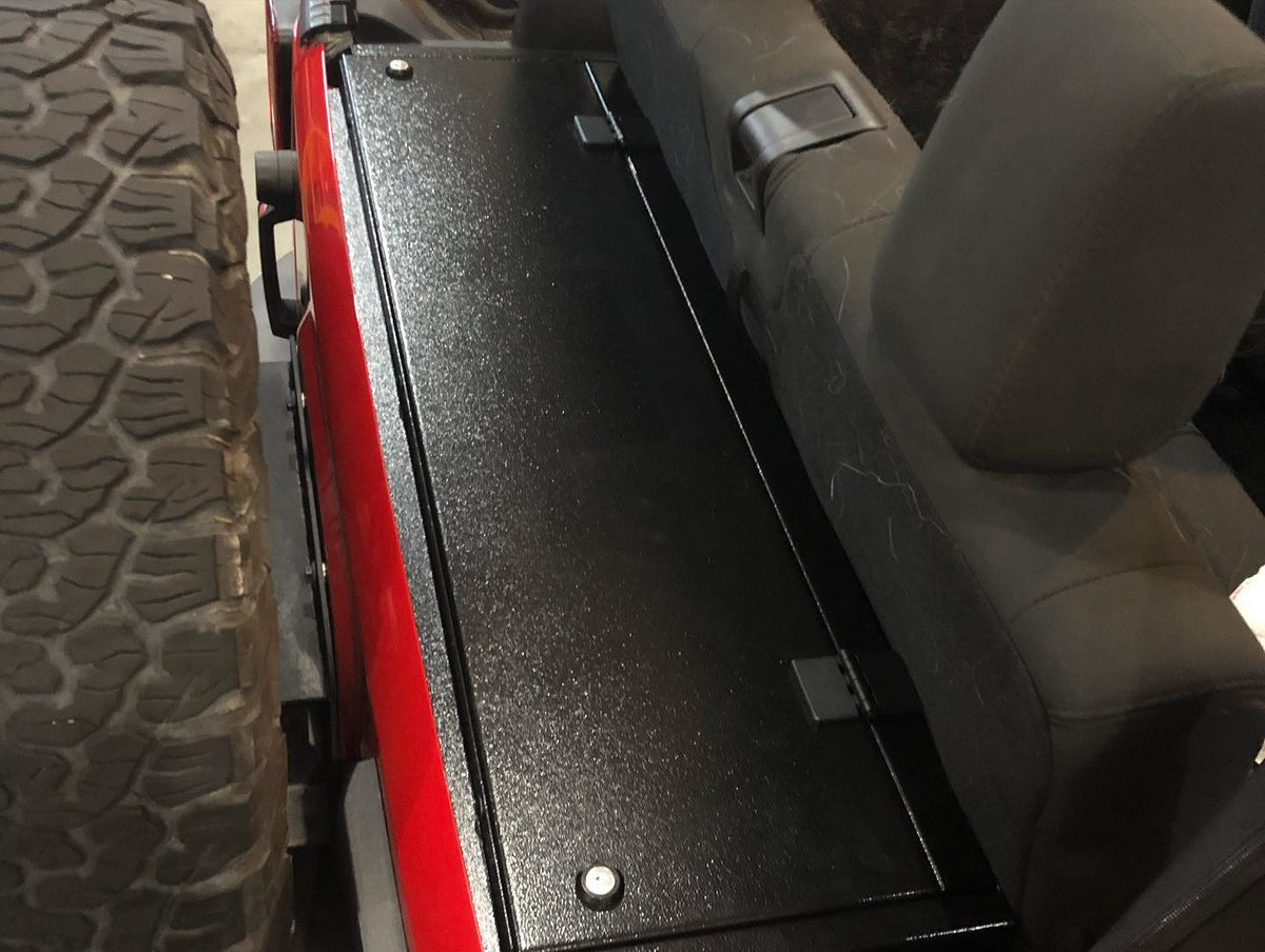 Locker enclosure lid seen from above beside the spare tire on a red JK