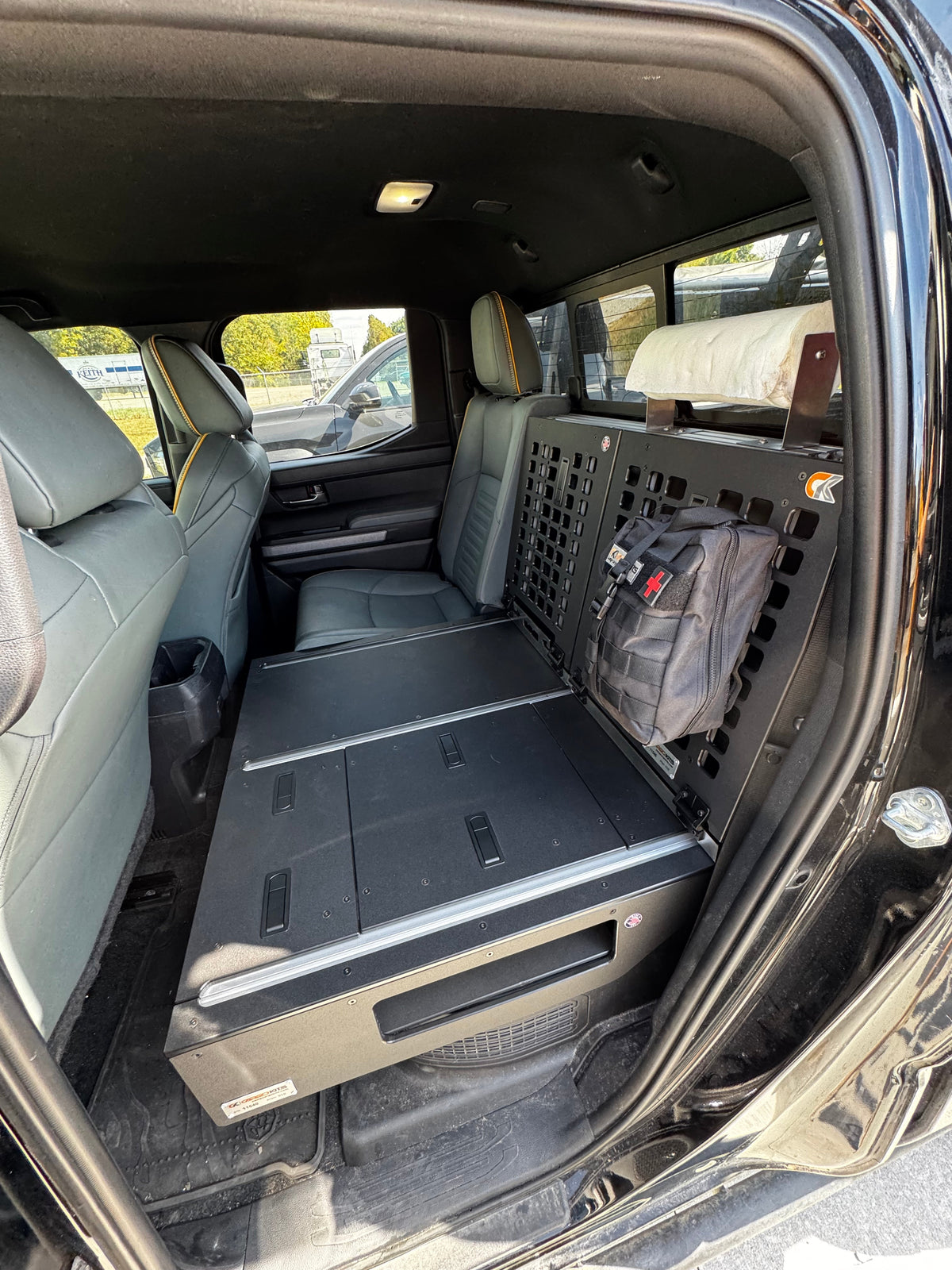 View through the open rear door of the CargoKits seat delete platform with its MOLLE rear panel, first-aid pouch, and paper towel holder