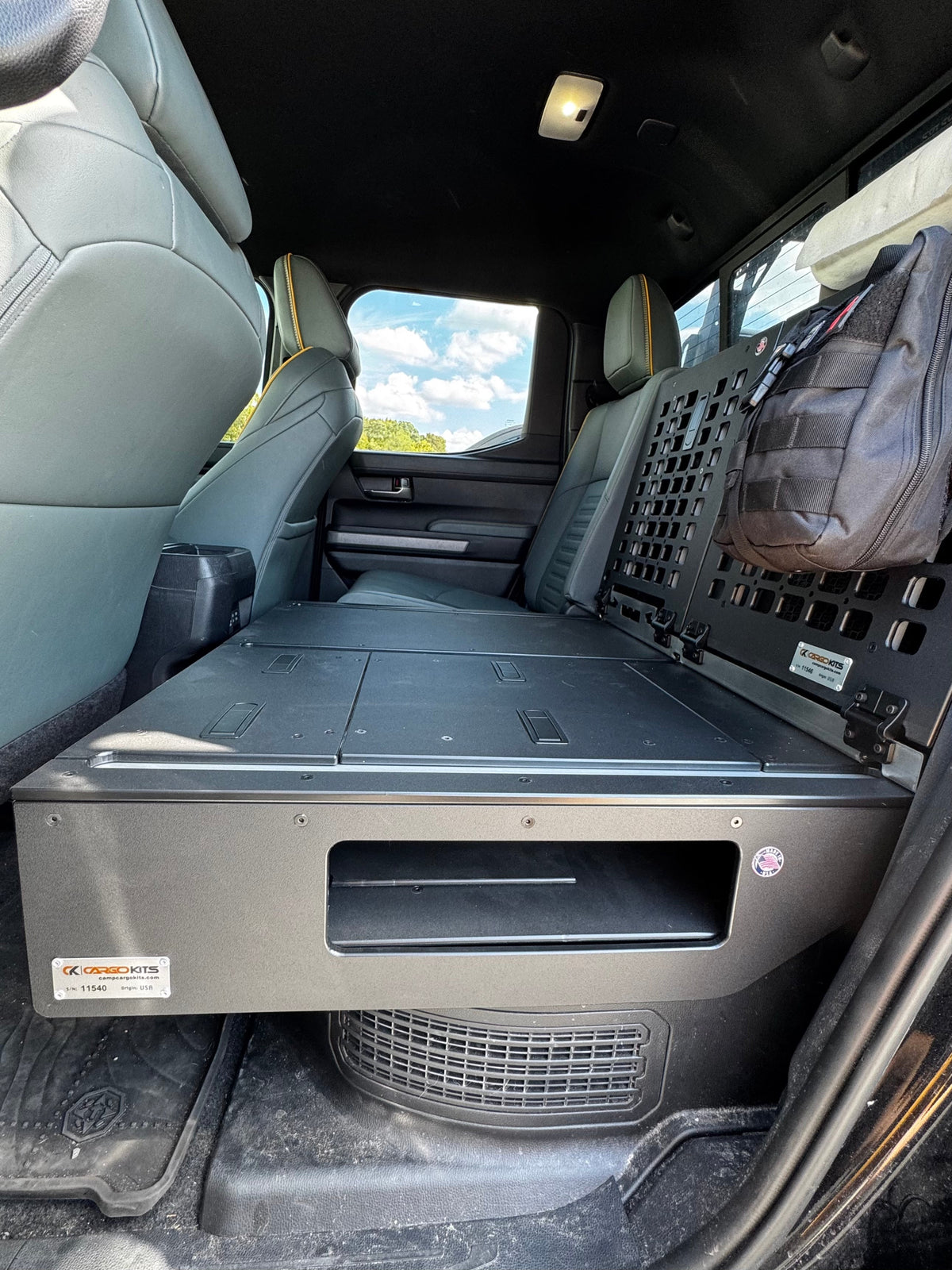 Front view of the CargoKits seat delete platform's drawer-style storage opening, with hatches on top and the MOLLE panel behind