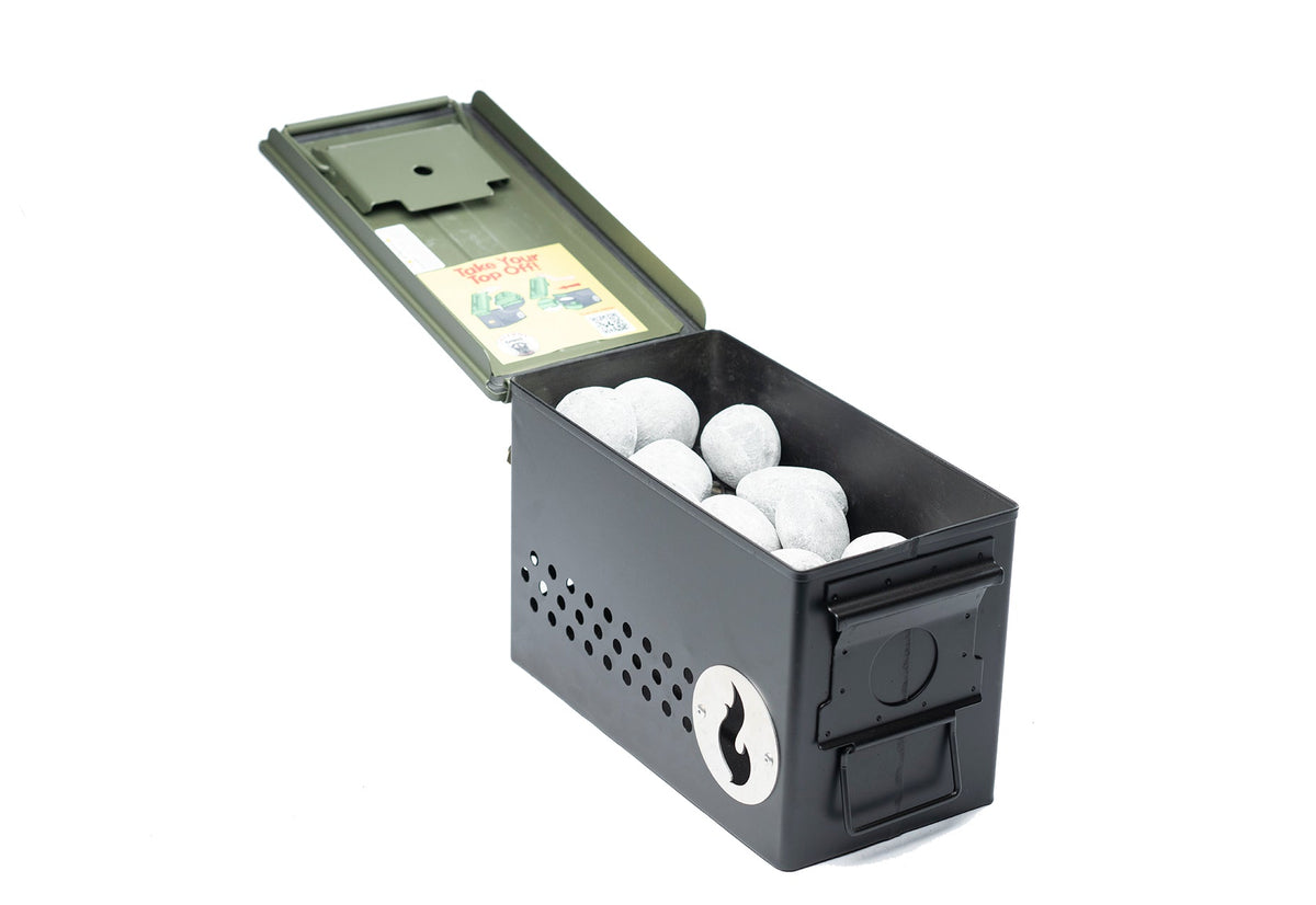 Olive green ammo-can-style firebox shown open and filled with light gray Hades Stones, studio shot on white background