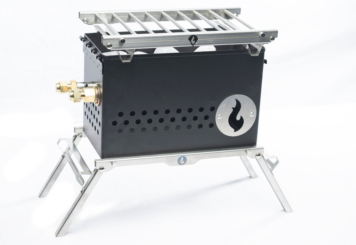 Black steel firebox with slotted grill grate on top and folding legs extended, studio shot on white background