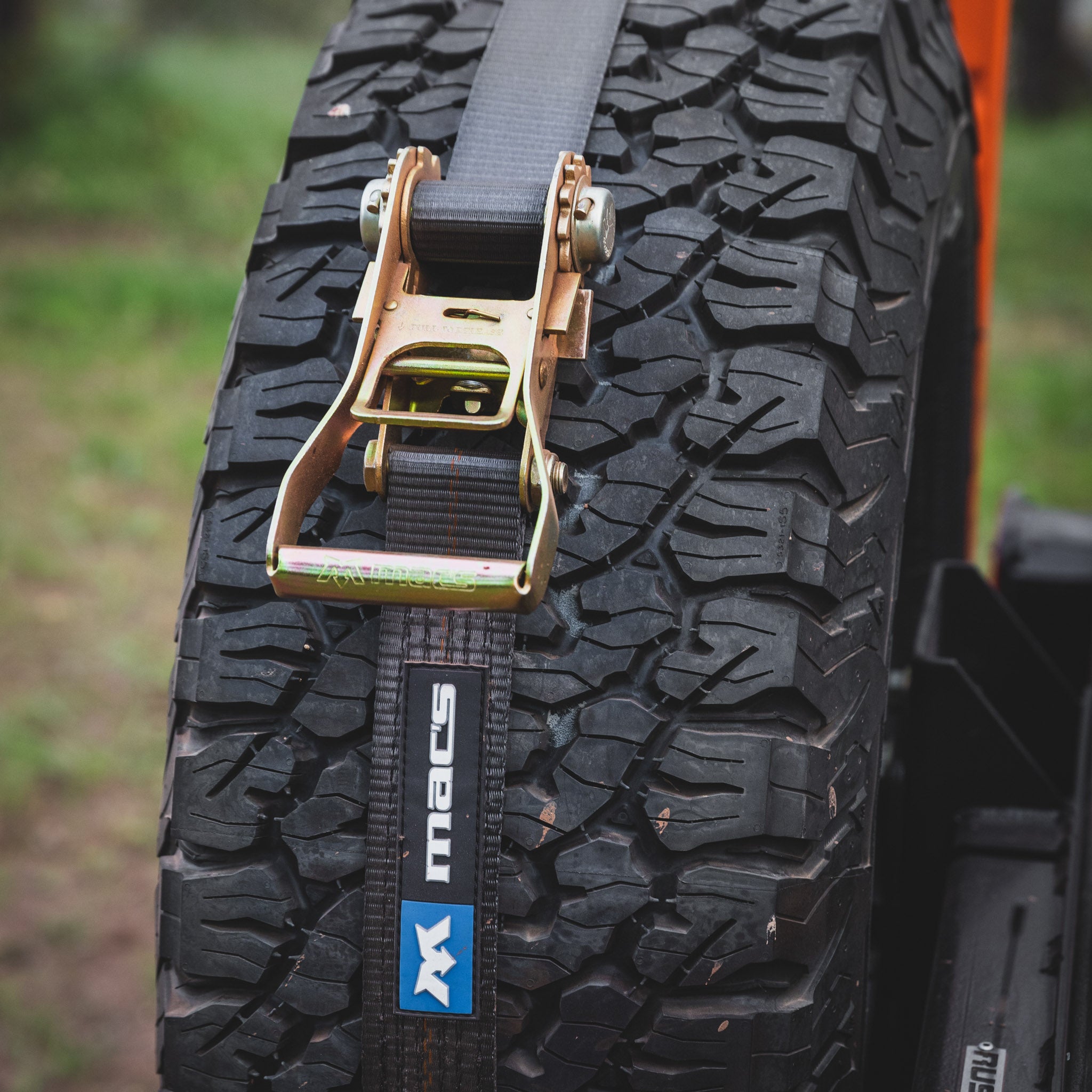 Maxtrax xtremes mounted on the Overland Kitted Spare Tire Mount on a Jeep- detail shot of the ratchet strap 