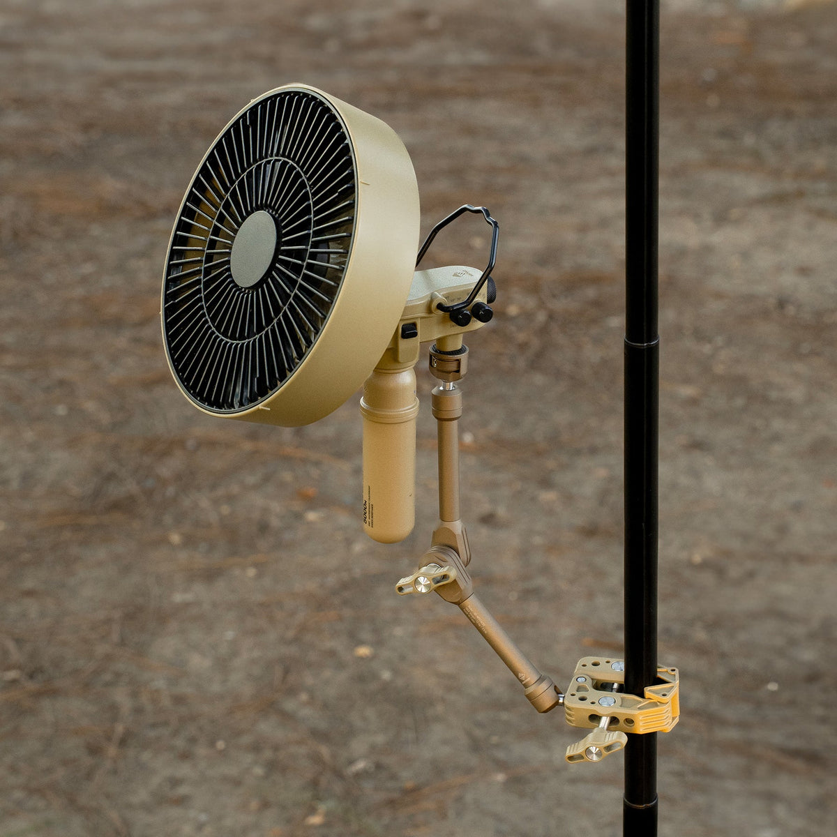 NESTOUT Clamp Arm in beige holding the FAN-1 fan, clamped to a pole outdoors