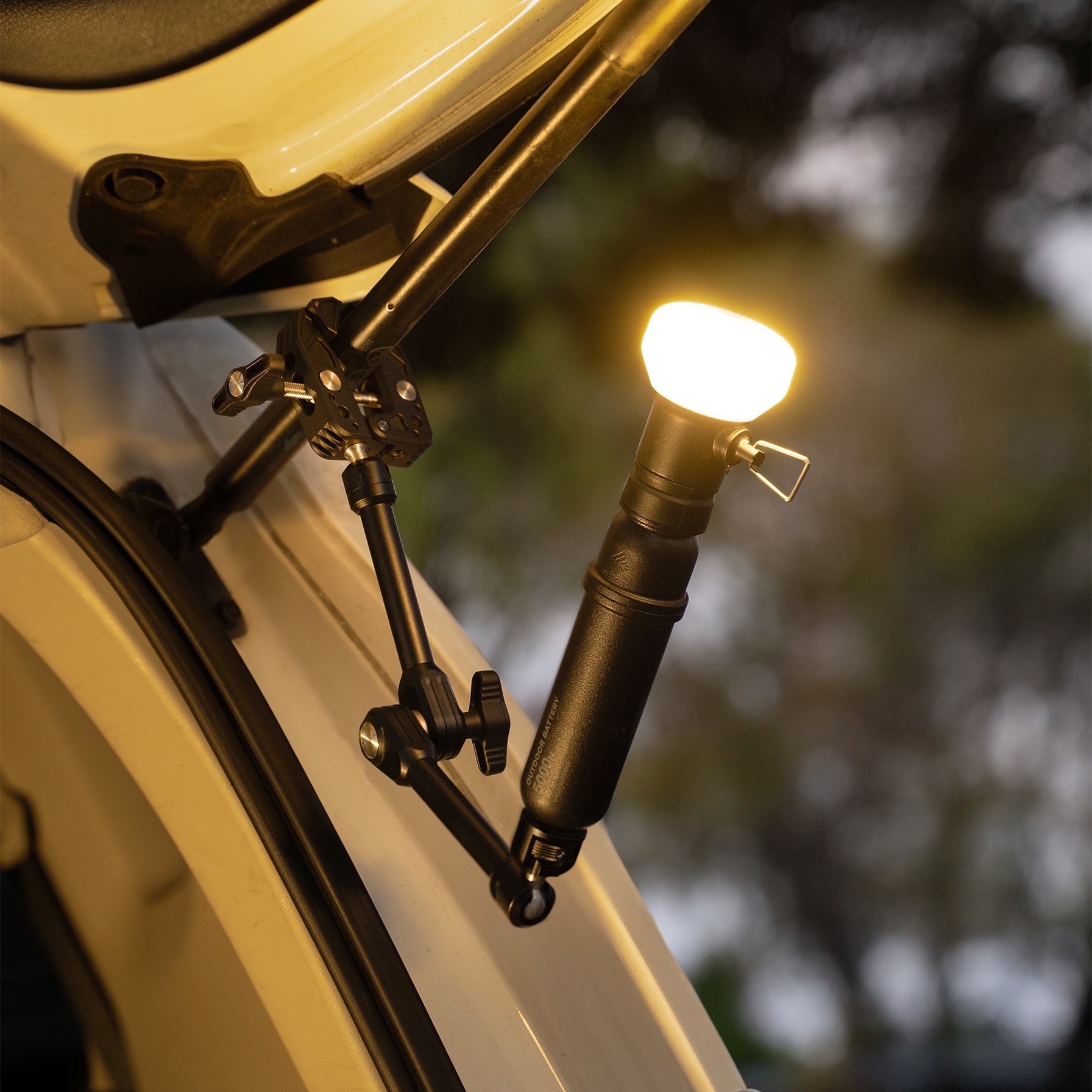 NESTOUT Clamp Arm mounted to a vehicle rooftop tent ladder with a lantern attached, lit at night
