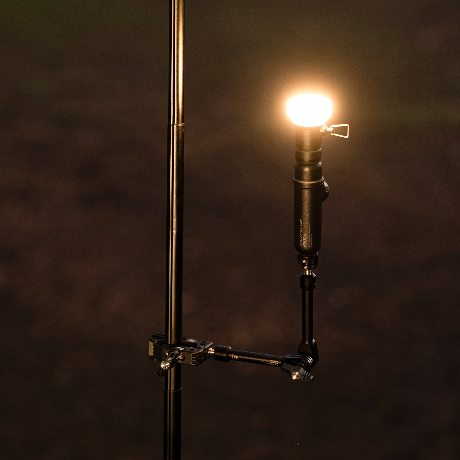 NESTOUT Clamp Arm holding an Outdoor Battery and light attachment, lit up at night