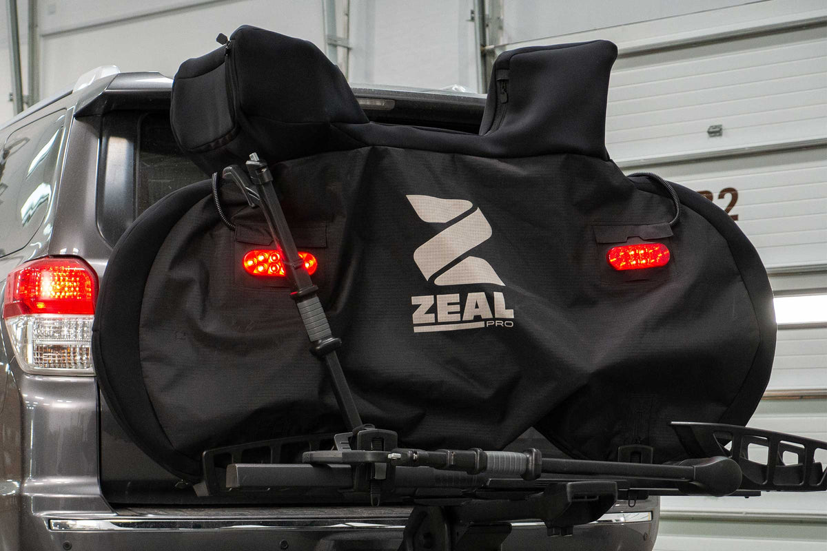 Road bike cover with both tail lights lit on a tray hitch rack behind a 4Runner