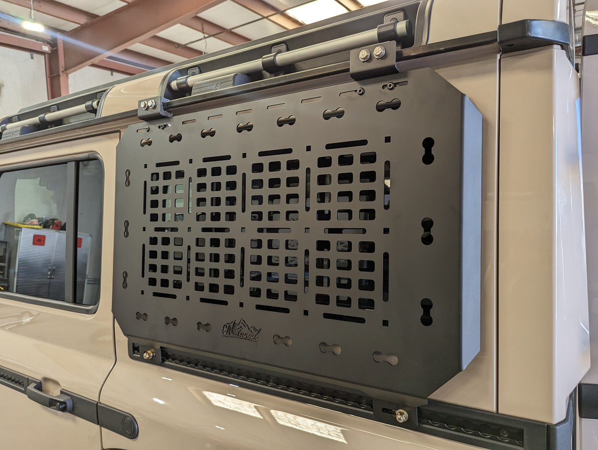 Empty black MOLLE panel installed on the rear side of a tan SUV near the window