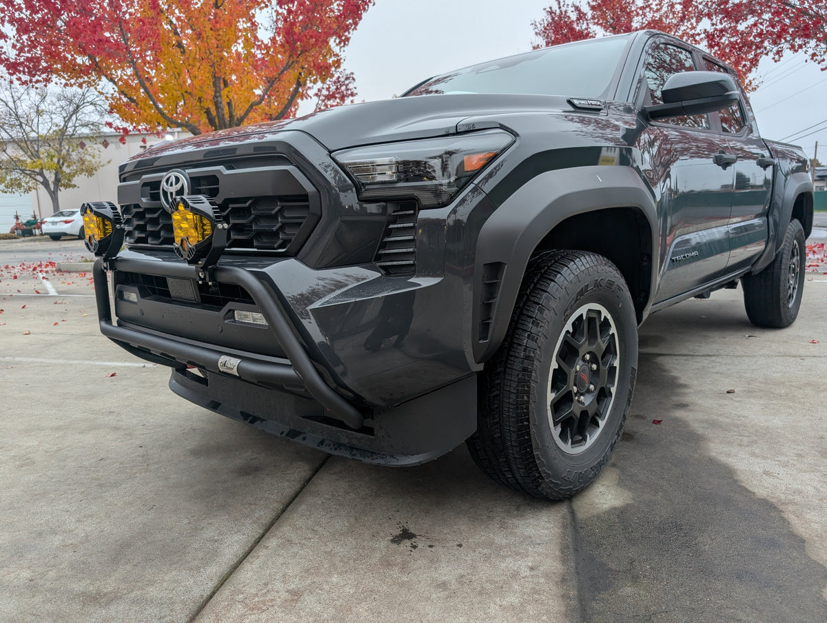 Gray Toyota truck with a black brush bar and amber lights on a concrete lot