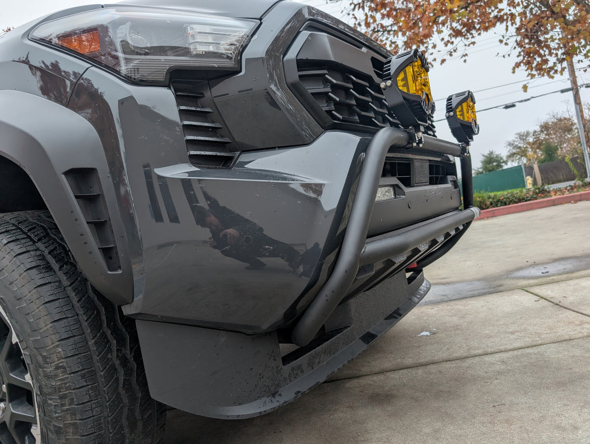 Close view of the brush bar curving around the front corner of a gray truck