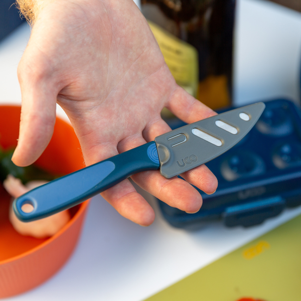 Hand removing the UCO Camp Paring Knife from its black protective sheath