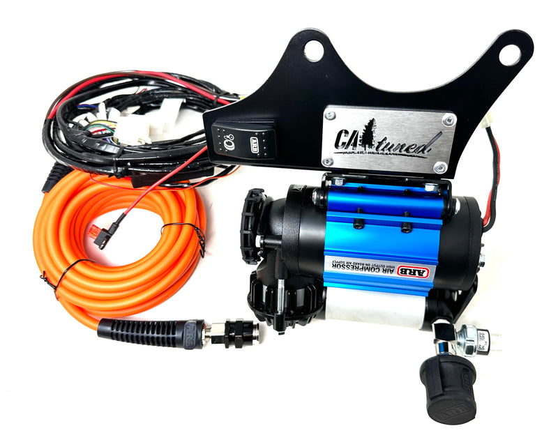 Blue compressor on a black bracket with an orange air hose and wiring