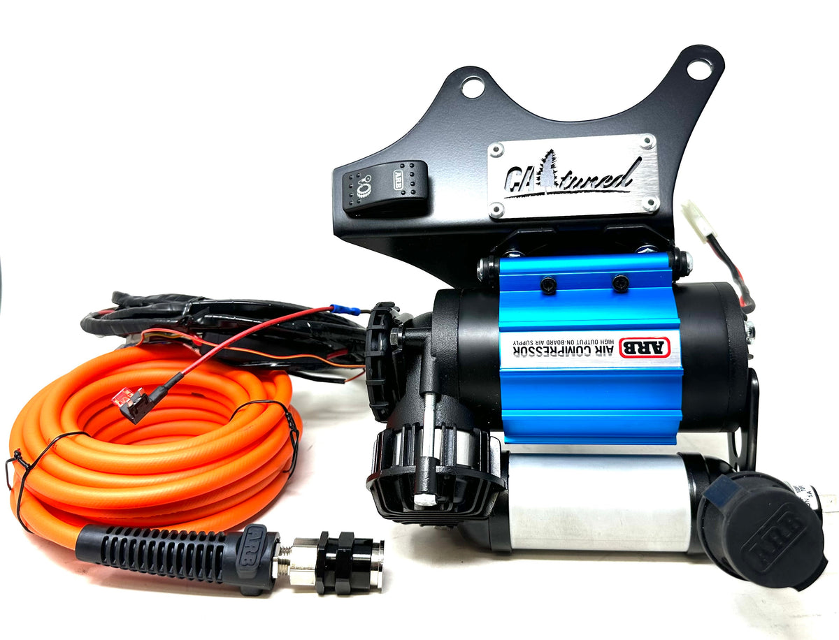 Blue compressor on its black bracket with coiled orange air hose and wiring