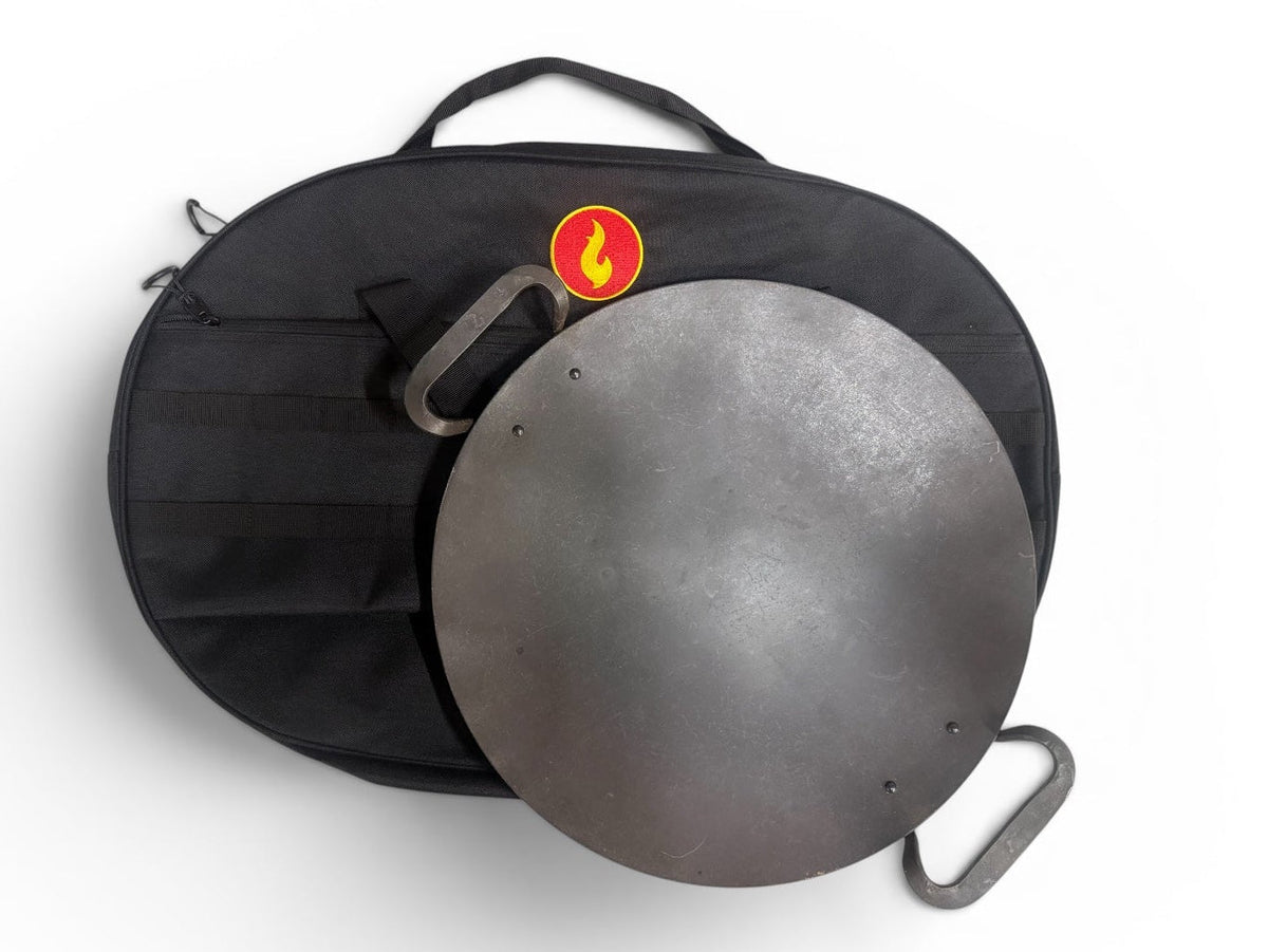 Round black steel griddle disc partially out of its black carry bag, showing the carry handle and flame logo patch
