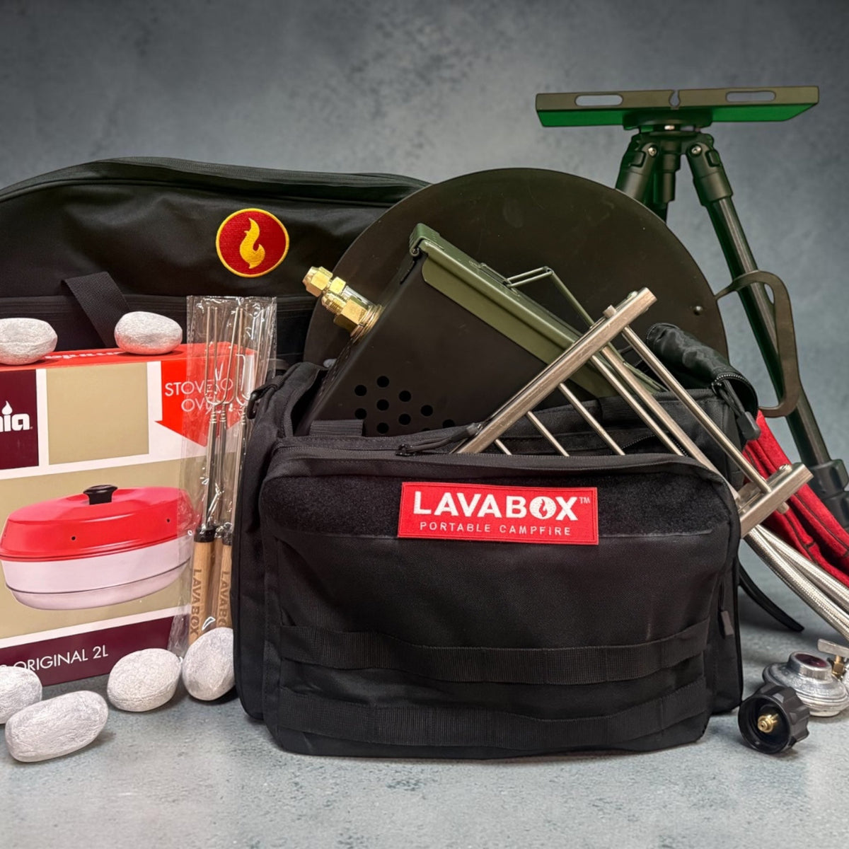 Overhead flat-lay of a full LavaBox kit including carrying bag, firebox, roasting forks, and tongs arranged on a concrete surface