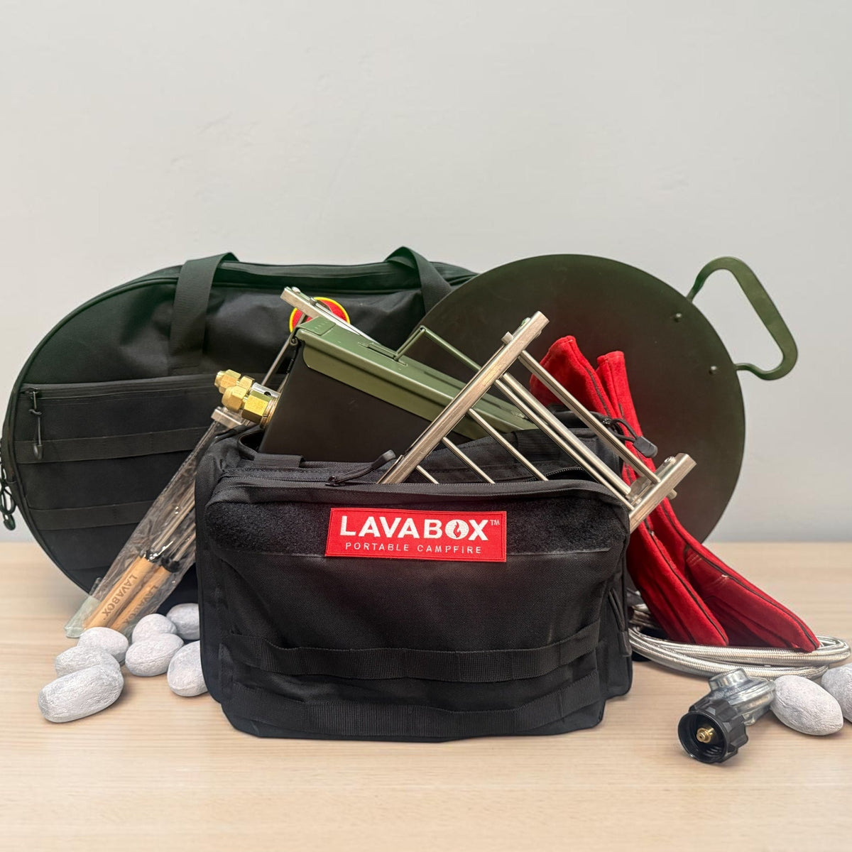 Overhead flat-lay of a full kit with fireboxes, roasting forks, gloves, hose, and Hades Stones arranged around an open black LAVABOX carry bag