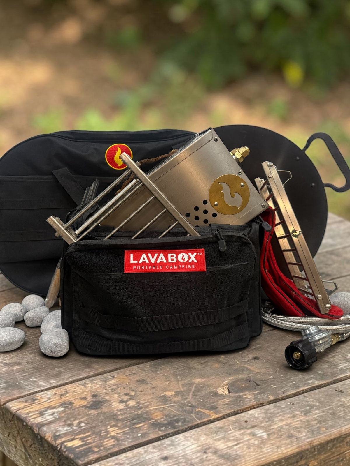 Overhead flat-lay of a stainless Hekla stove kit with roasting forks, tongs, and Hades Stones packed alongside its LAVABOX carry bag