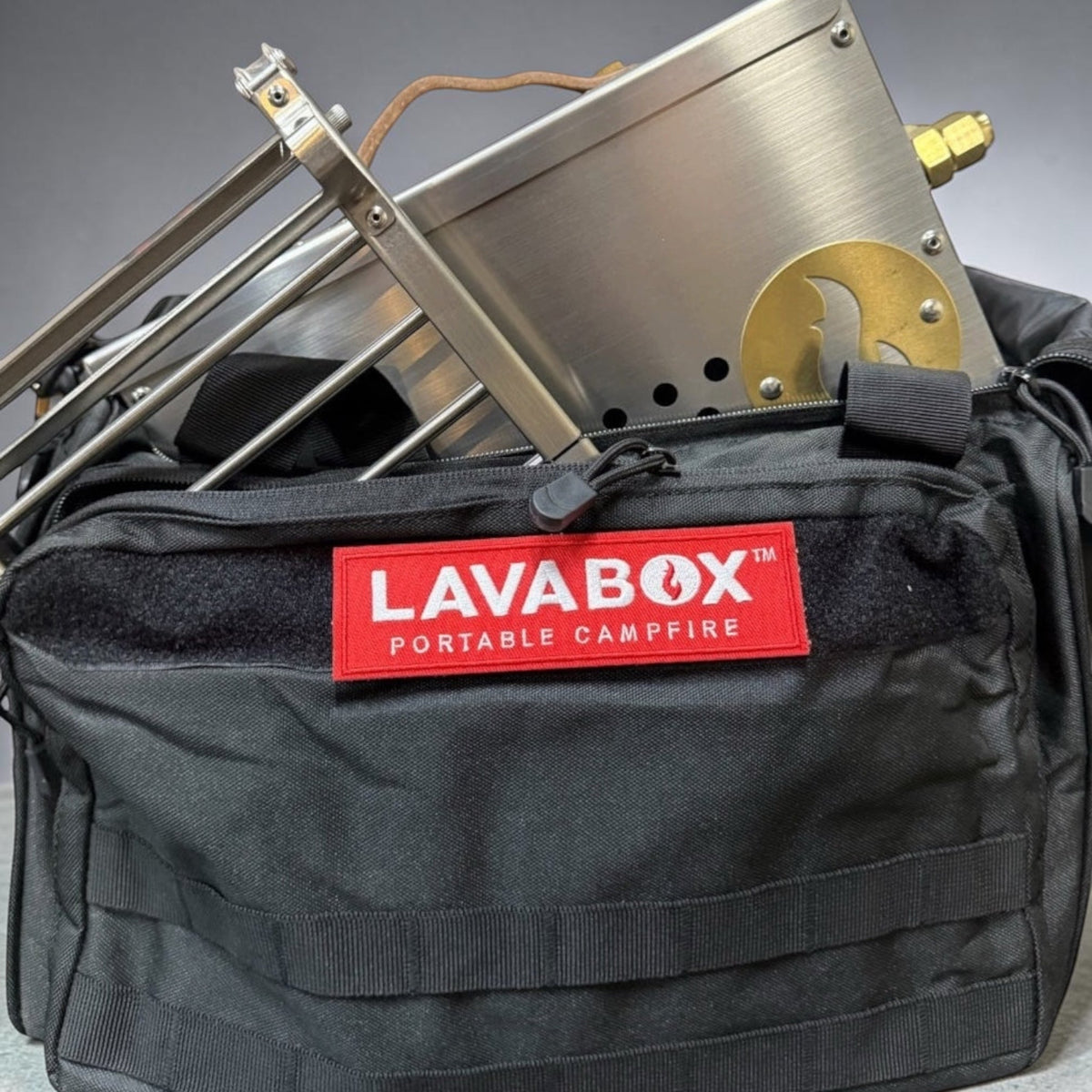Stainless steel firebox with leather handle and roasting fork packed into an open black LAVABOX carry bag