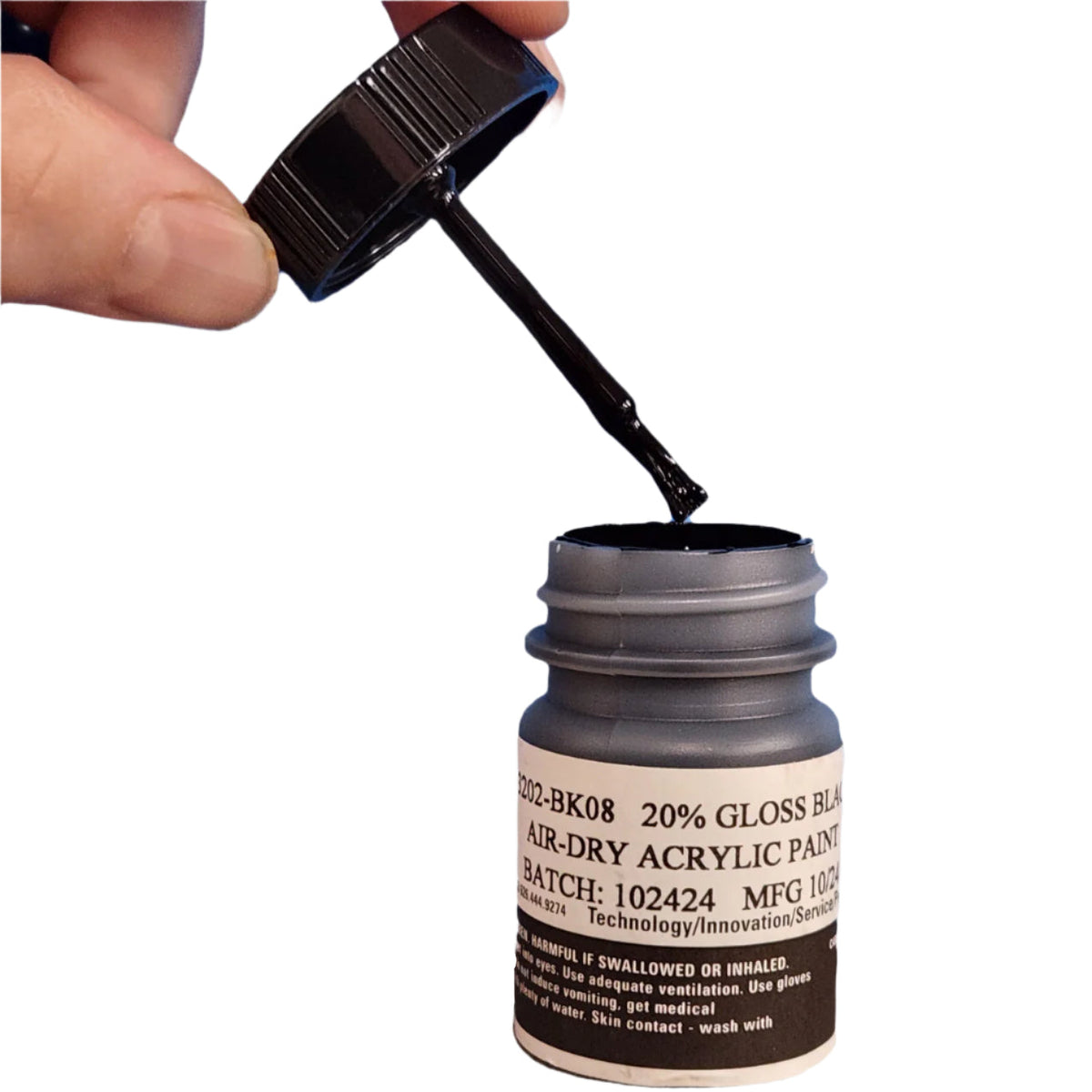 Brush cap lifted out of the black touch-up paint bottle