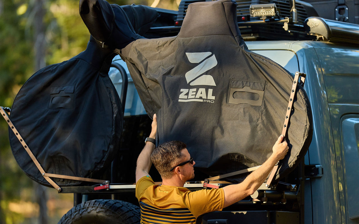 Rider fitting a covered mountain bike onto a hanging hitch rack at the back of an SUV
