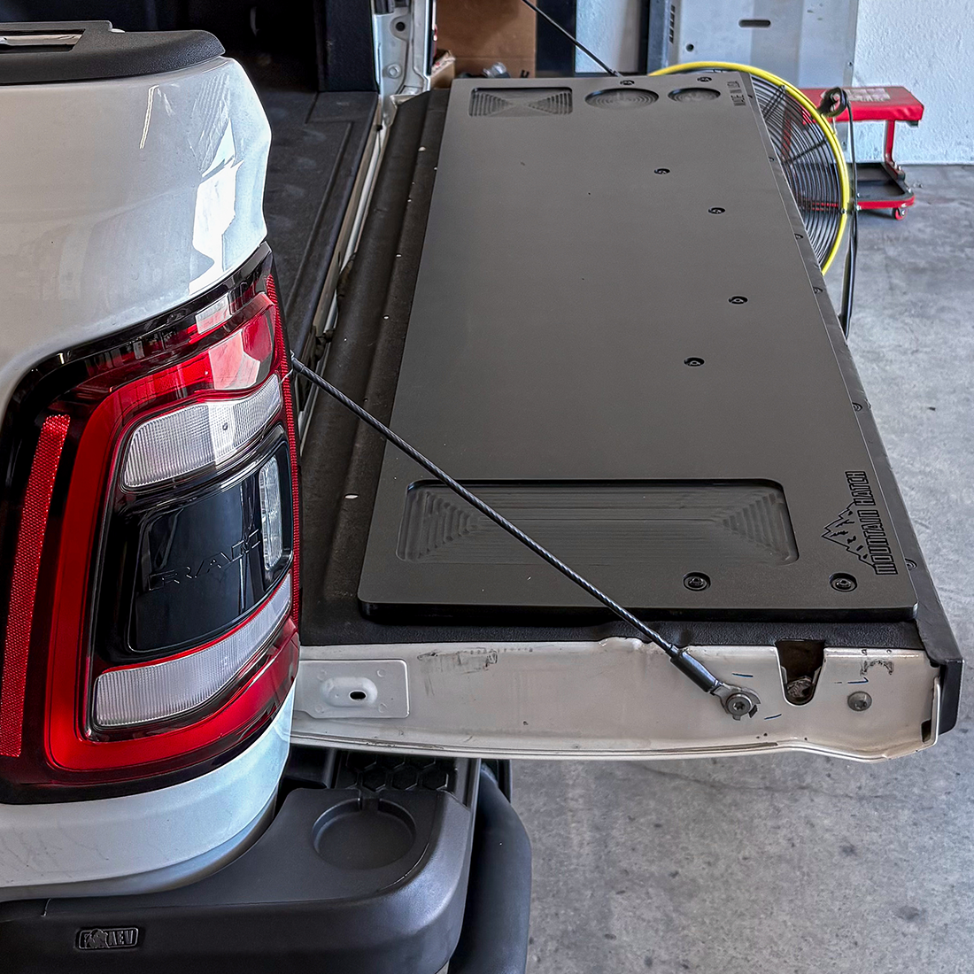 Mountain Hatch tailgate table installed on a white 2019+ Ram 1500 tailgate, recessed tray and drink holders visible