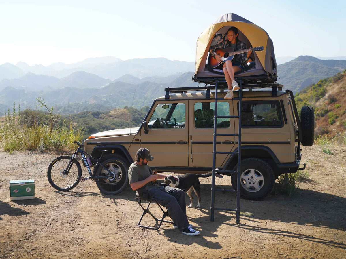 C6 Rev Rooftop Tent X (Element) – on a vehicle roof at camp, person seated below