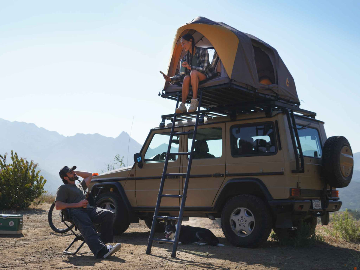 C6 Rev Rooftop Tent X (Element) – set up on a vehicle roof with ladder, person seated nearby