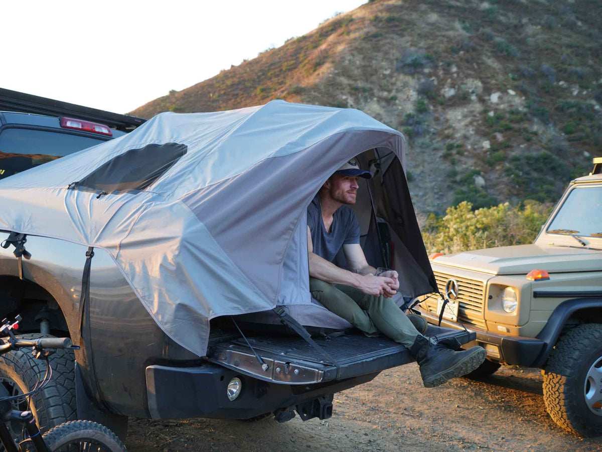 C6 Rev Pickup Truck Tent – person sitting at the tailgate inside the tent