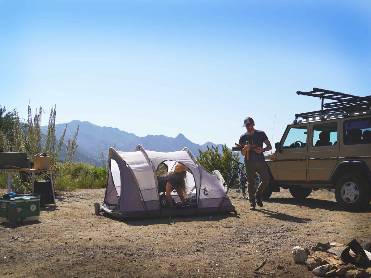 C6 Rev Rack Tent (HellaStorm) – camp scene with a ground tent and vehicle