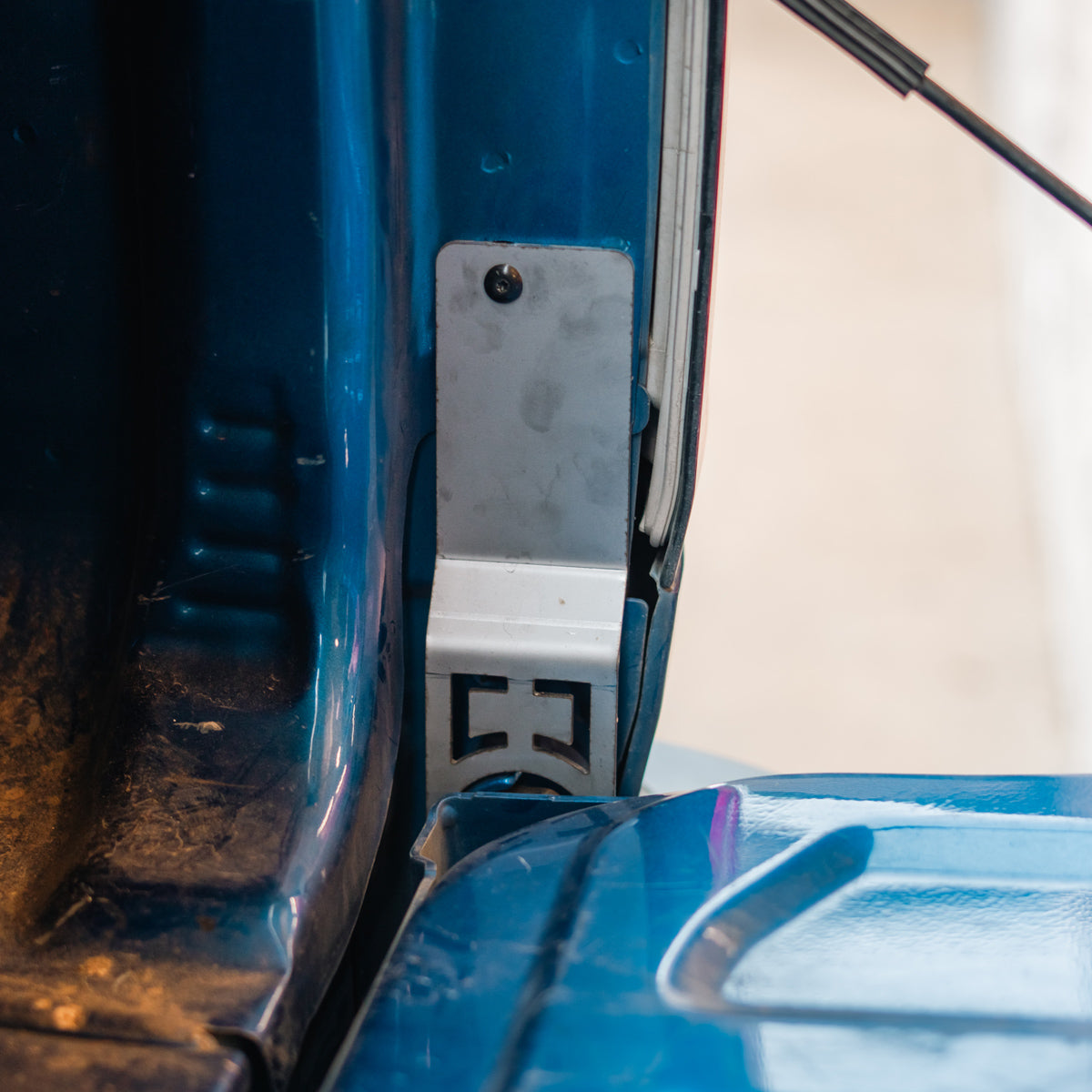 Cali Raised LED tailgate theft protector installed on a blue Chevy Colorado tailgate hinge, close-up
