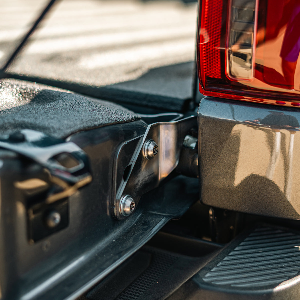 Cali Raised LED tailgate theft protector installed on a Ford F-150 tailgate hinge, wide view showing the taillight and side step