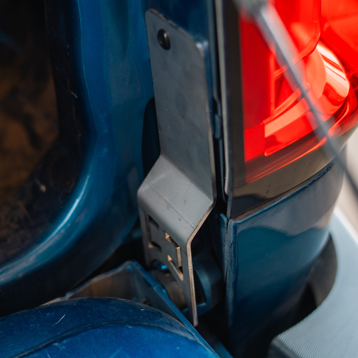 Cali Raised LED tailgate theft protector installed on a blue Chevy Colorado tailgate, wider view showing the taillight