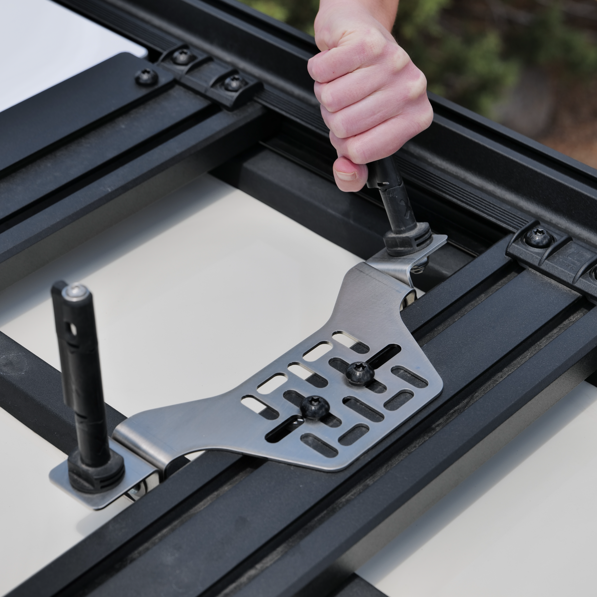 Stealth Folding Mount with Maxtrax Pins attached, hand is folding one of the pins flat