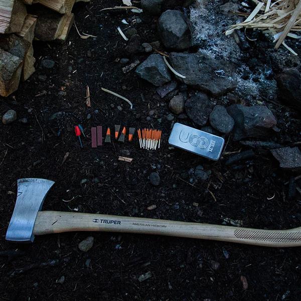 Fire starting materials and kindling laid on the ground near a hatchet