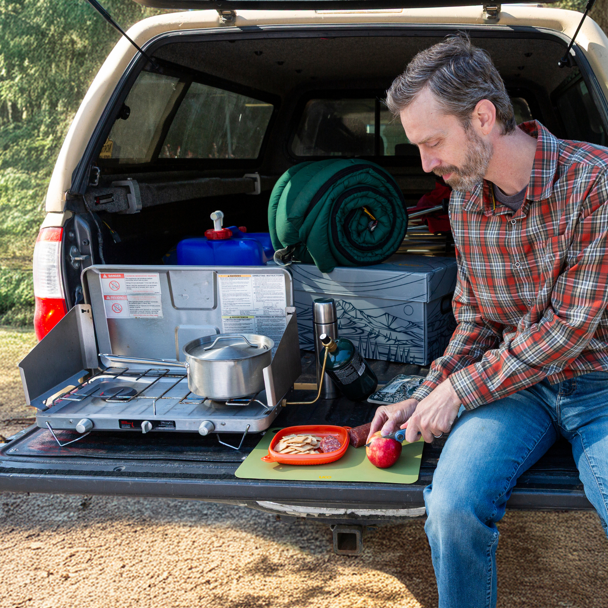 Man loading gear into a truck bed near a folding camp table
