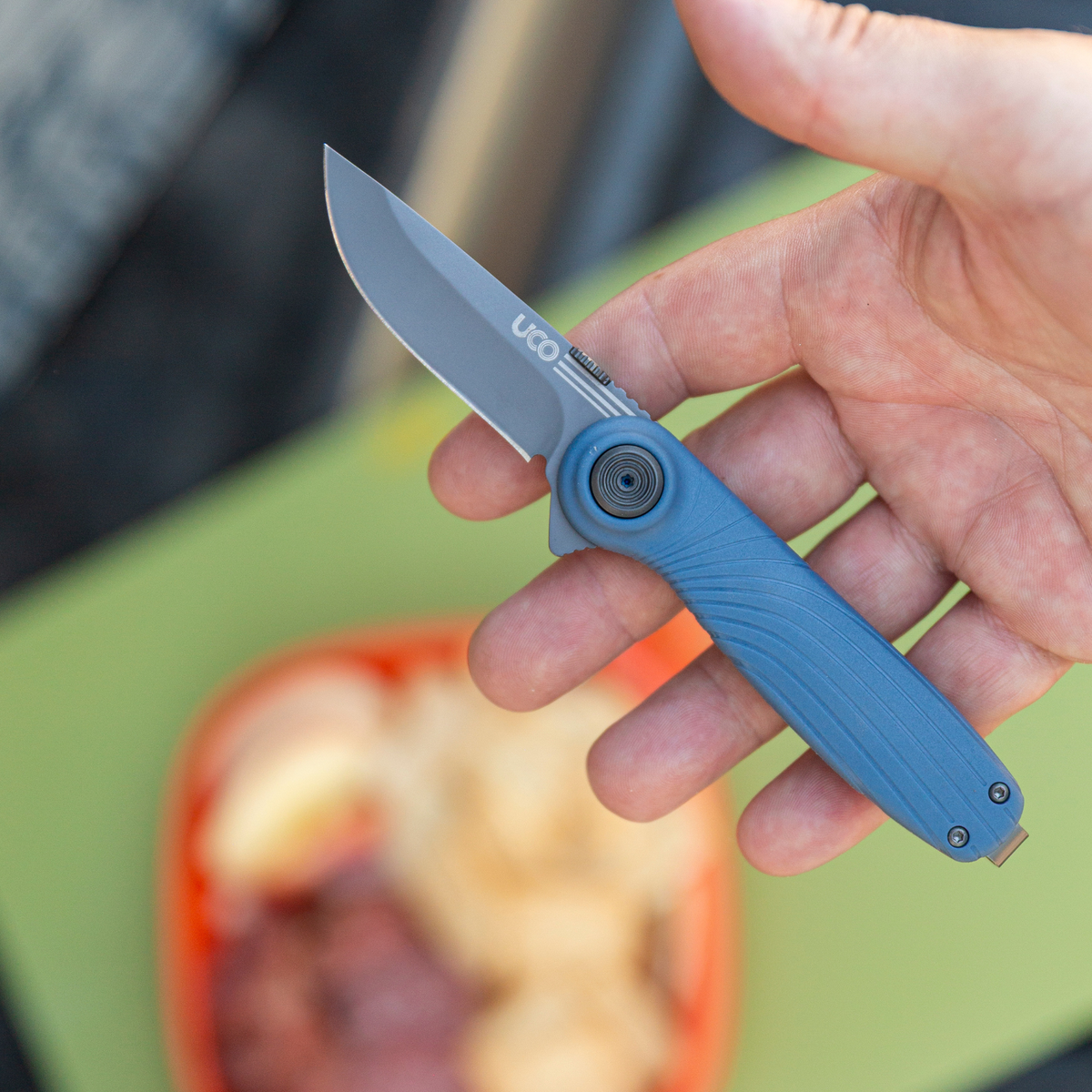 Gray-blue UCO Whidbey Mini folding knife open in hand outdoors